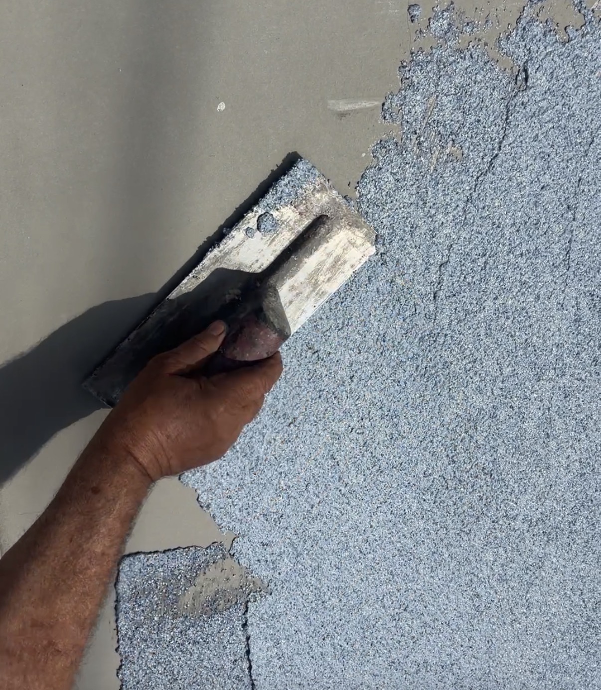 Applicator troweling MP Grani-Flex flake coating onto a concrete wall